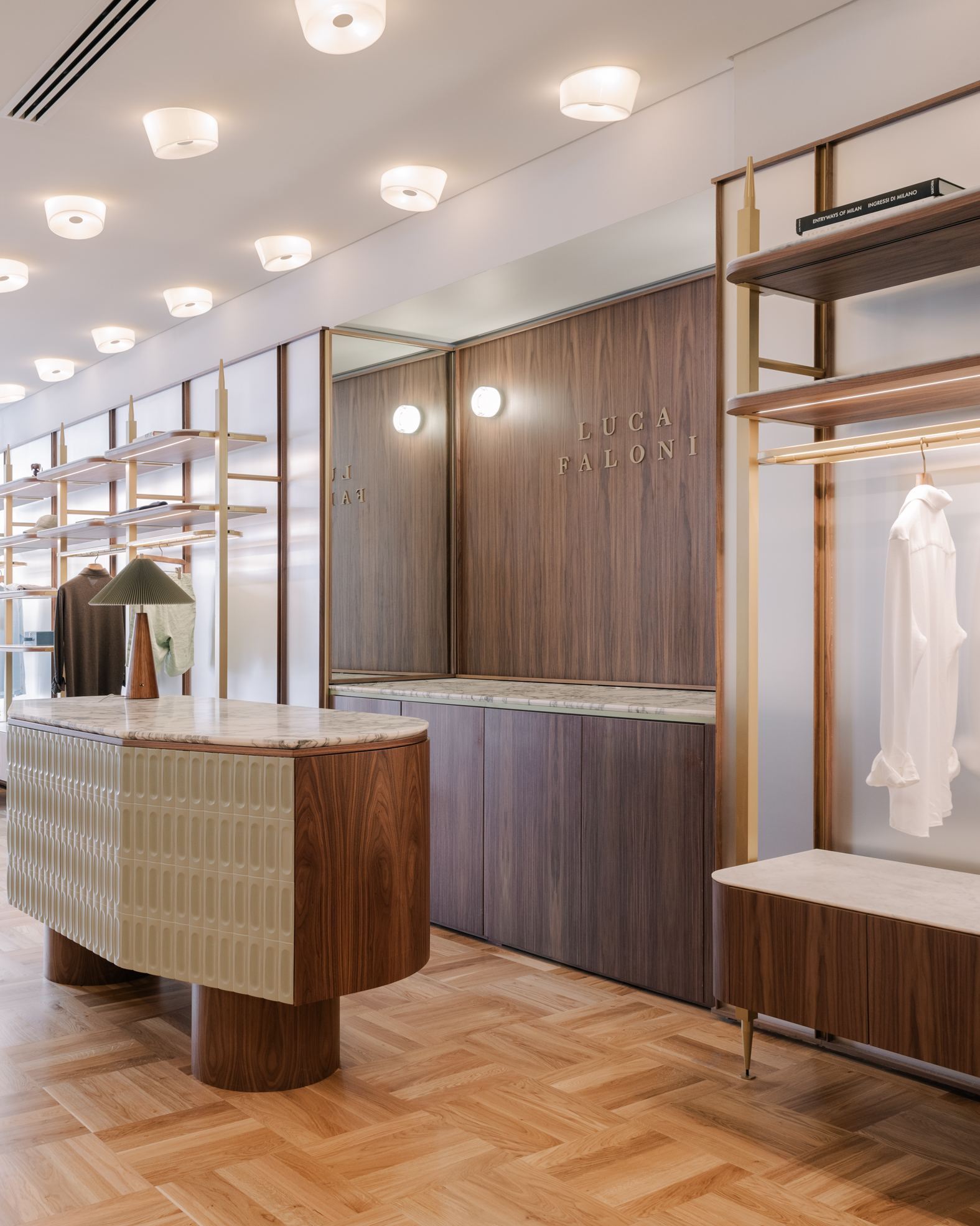 Cash desk in dark wood and green tiles in a quiet luxury menswear shop.