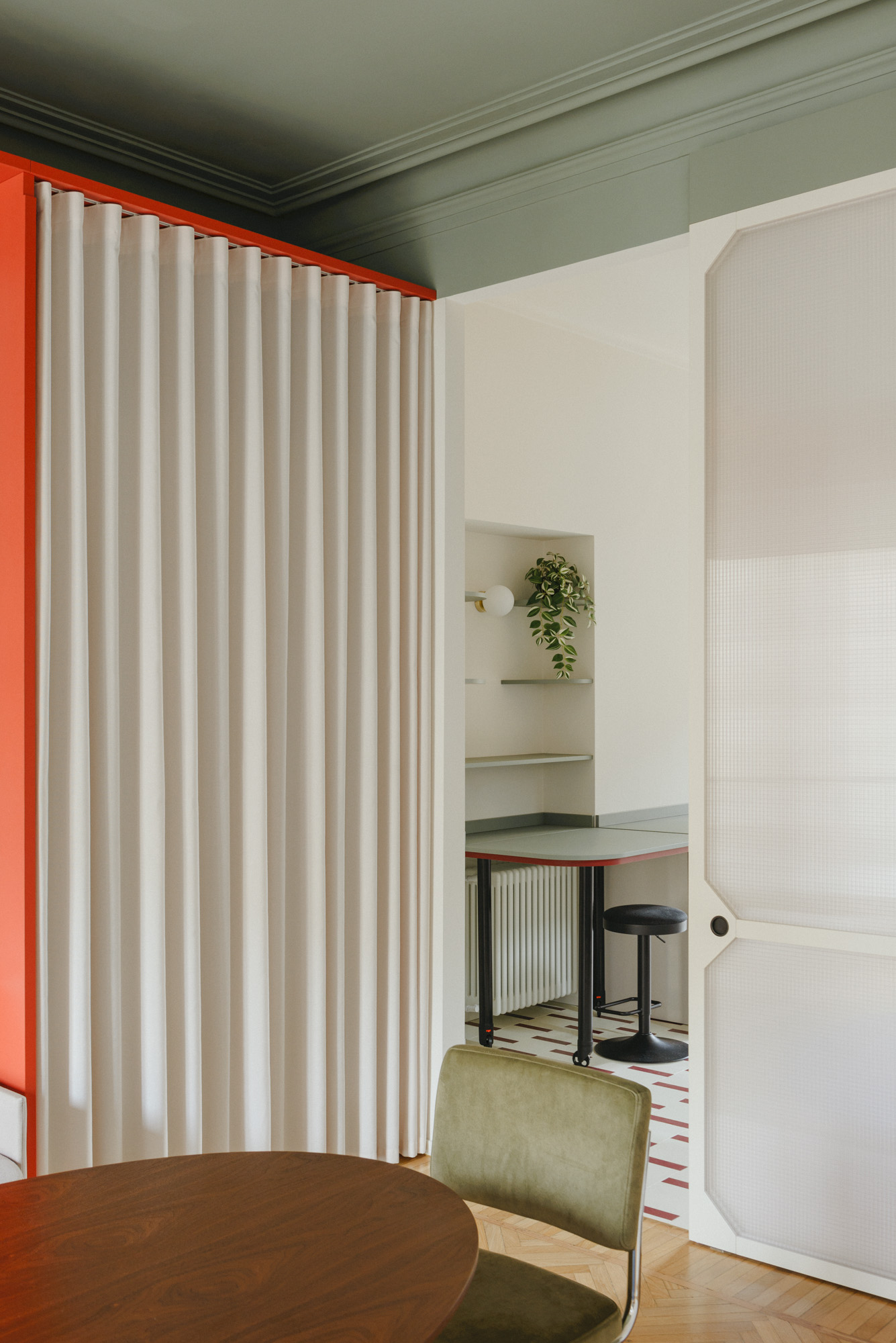 Dining room with sage green ceiling and chair, wooden table and floor, white curtain and semi-transparent door.
