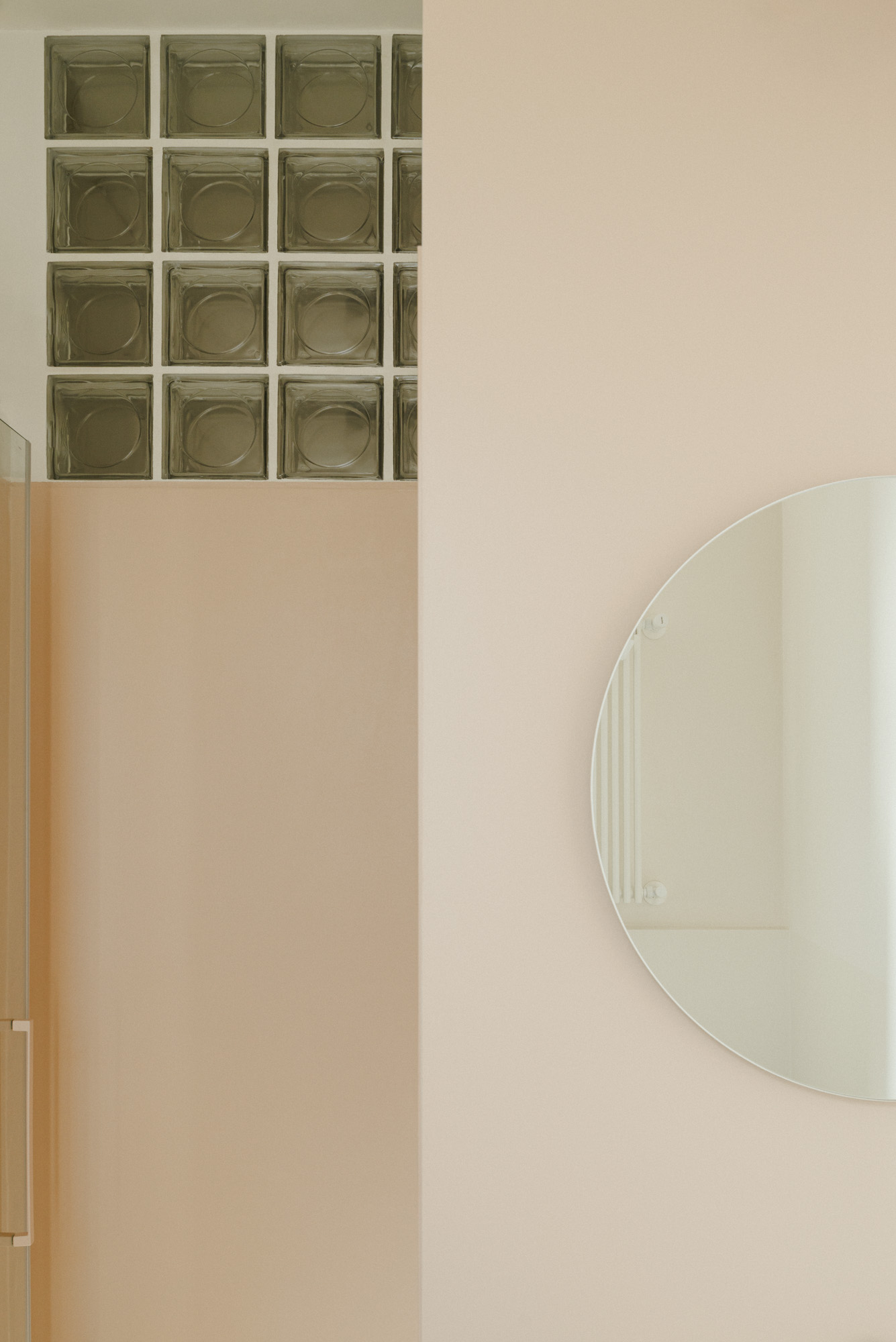 Glass bricks and circular mirror incorporated in a cream toilet.