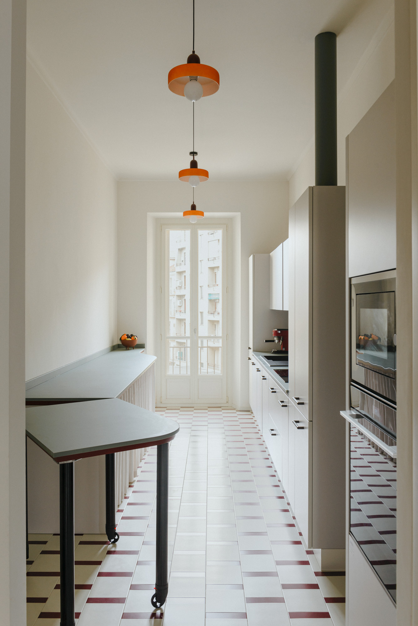 Modular small kitchen with white cabinets, green table, and red lights.