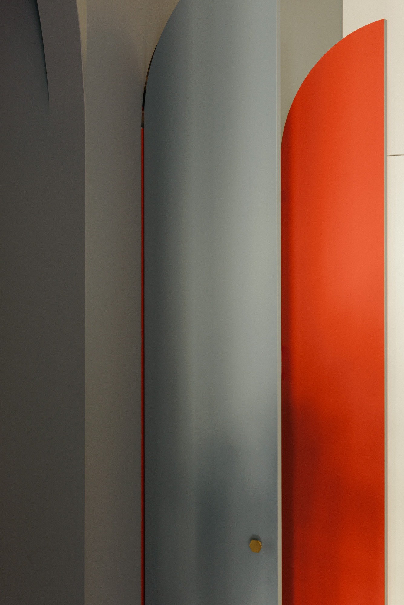 Red interior of an arched wardrobe, contrasting with the sage green exterior.