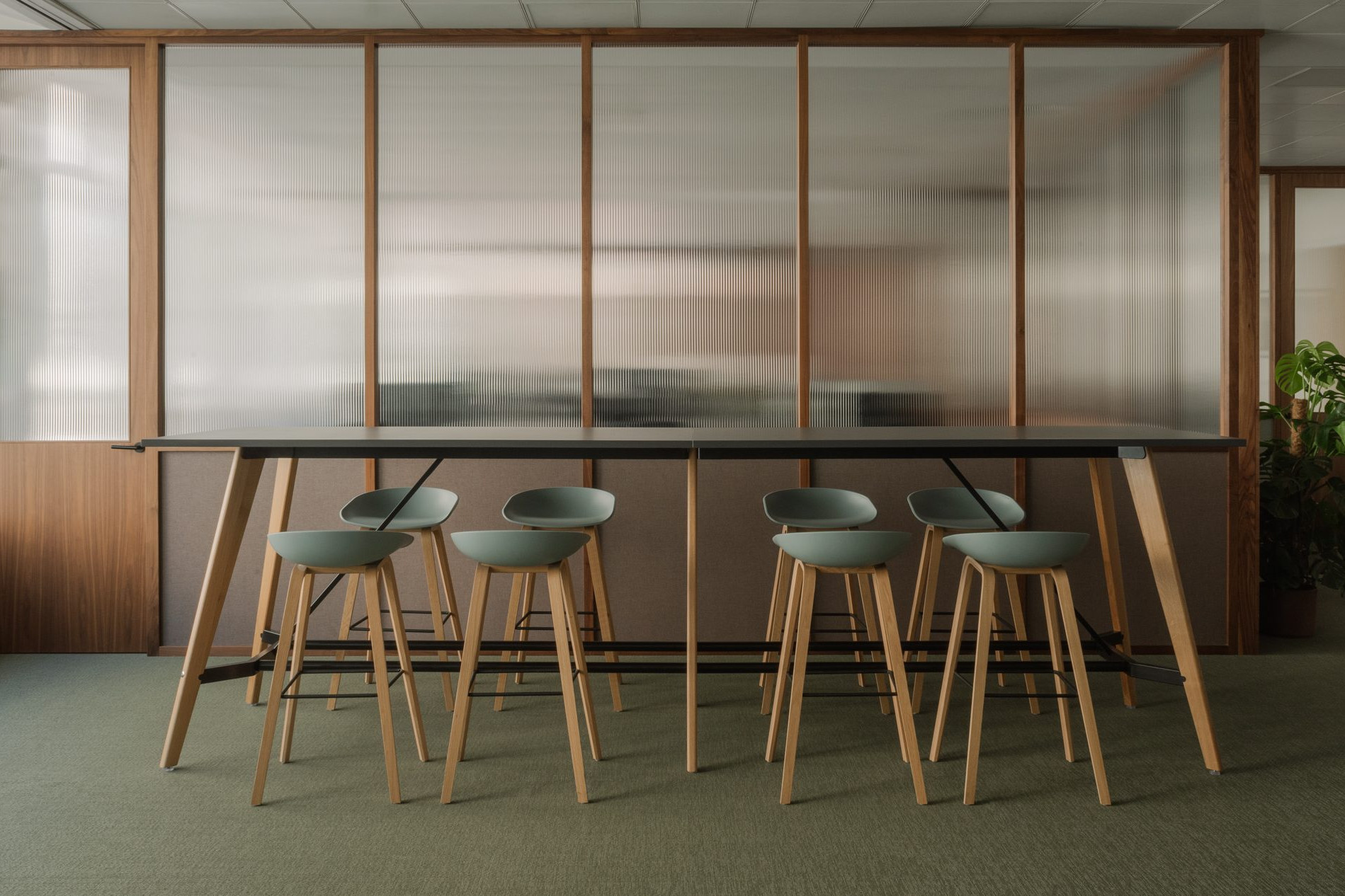 Elegant office break room with green floor, custom dark wood furnishings and walls made of Canaletto walnut panels with fluted glass.